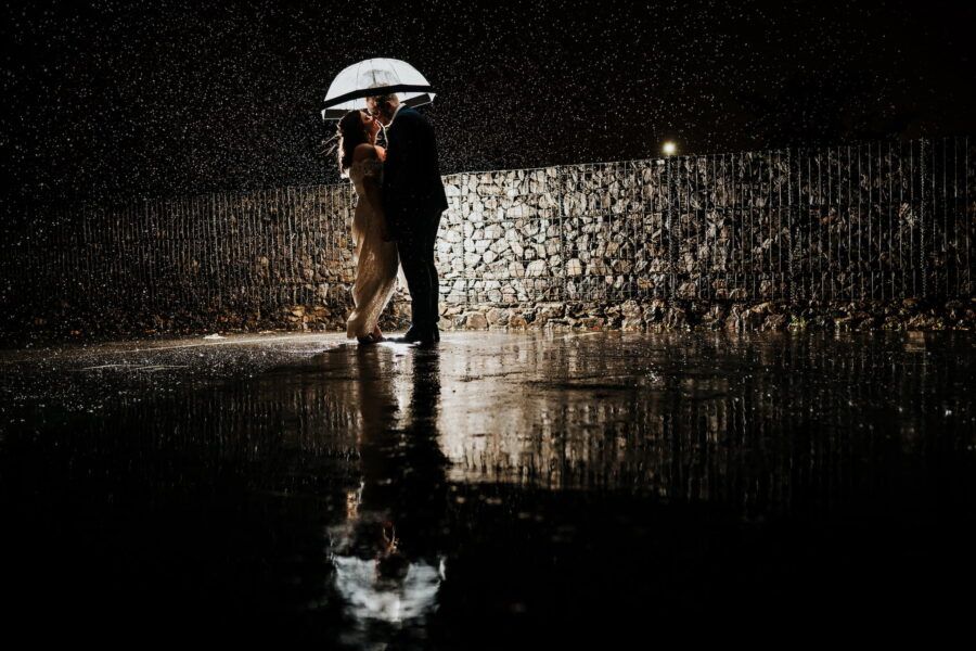 Artistic silhouette wedding photography against dark background with dramatic reflections.