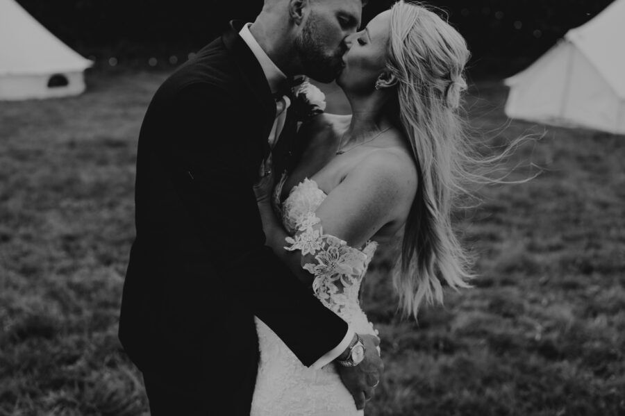 Dramatic black and white portrait of newlyweds sharing an intimate moment outdoors.