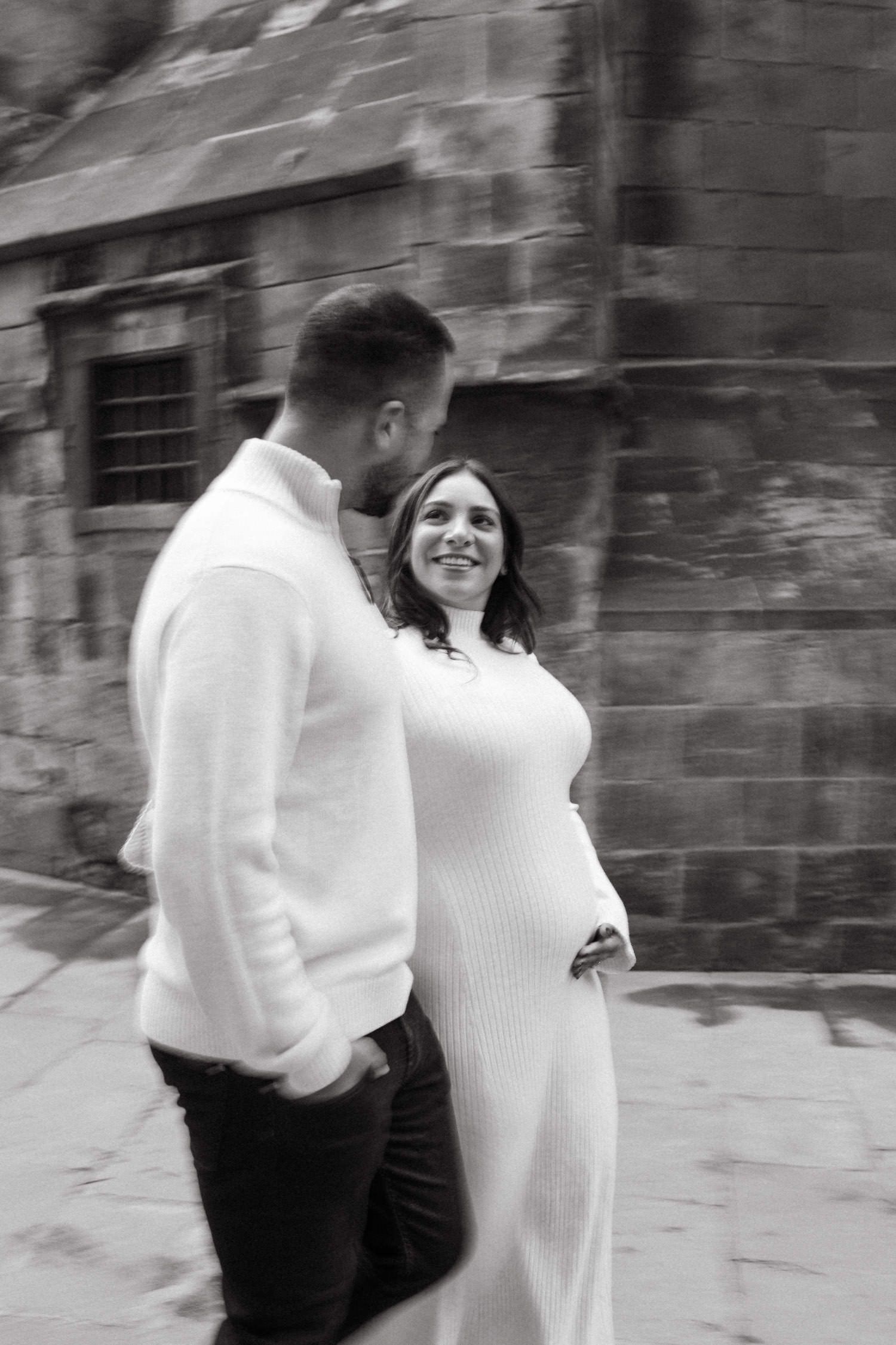 Black and white maternity photos captured in a historic stone corridor.