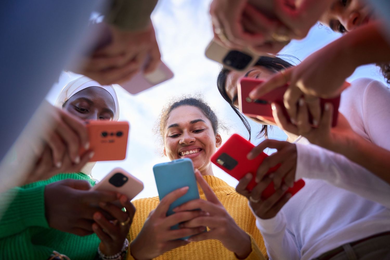 Multiple hands reach towards the center of the frame during a cheerful group interaction.