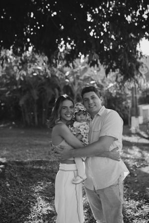 A black and white outdoor family portrait taken under leafy trees.