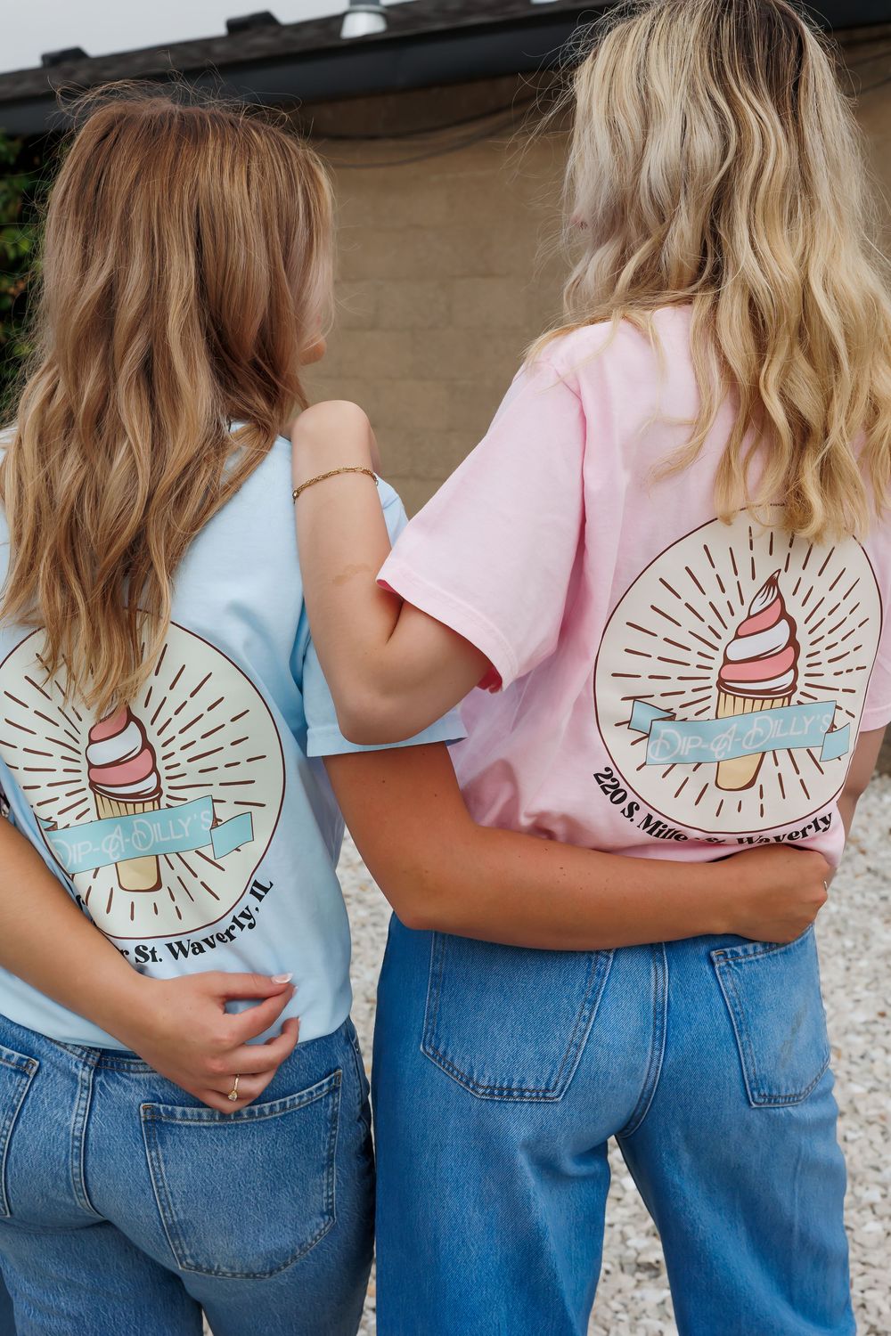 Back view of two people wearing matching ice cream themed t-shirts in blue and pink colors.