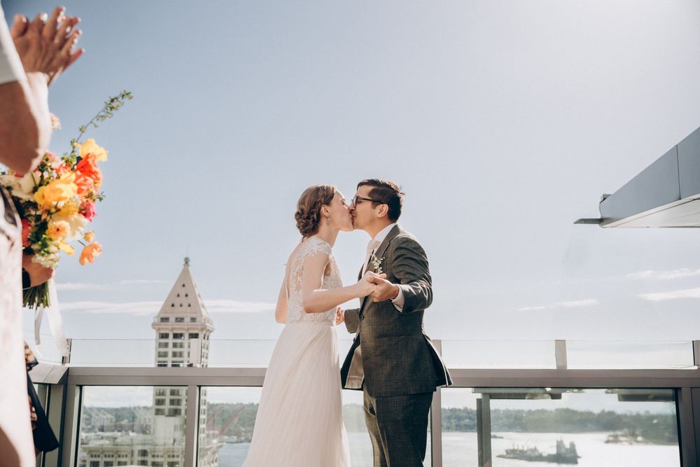 A romantic rooftop wedding ceremony with a couple sharing a kiss under the bright sky at Seattle Courthouse