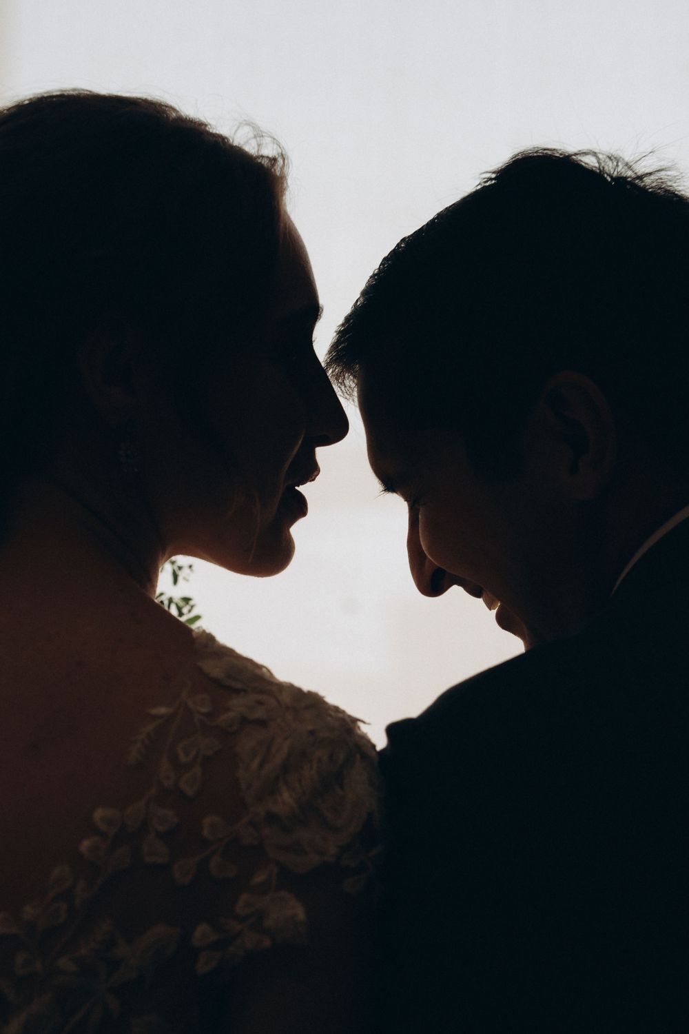 Romantic silhouette of couple in intimate close-up against bright backlight creating dramatic contrast.