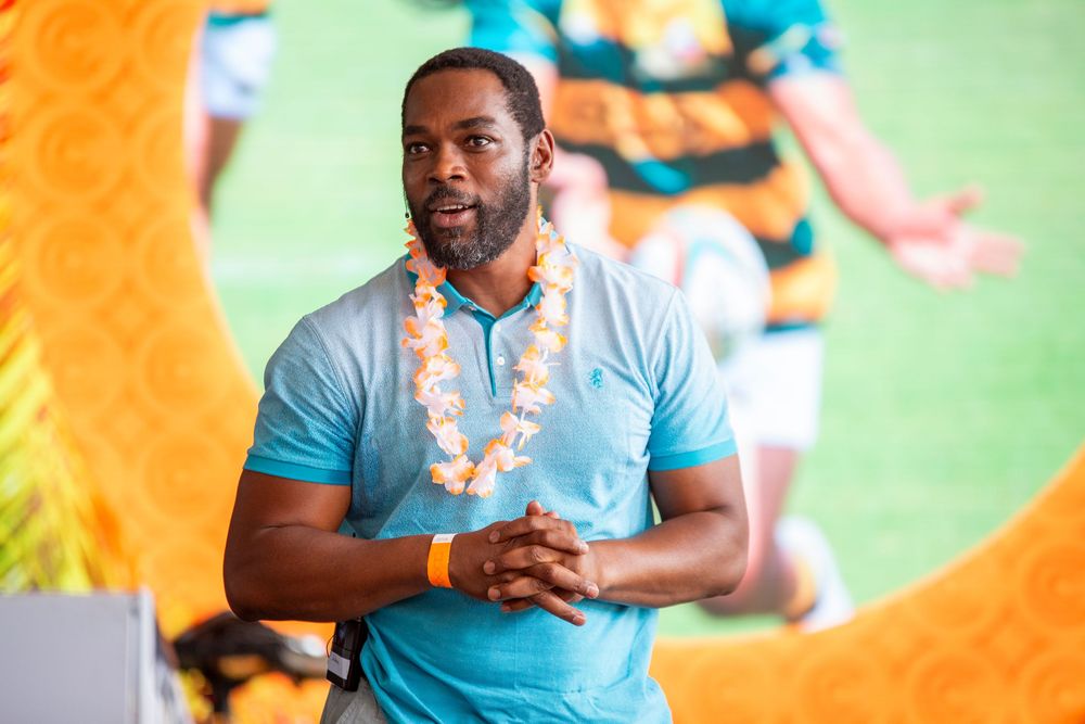 Athletes in light blue uniforms are shown during a sporting event with vibrant orange lighting effects in the background.