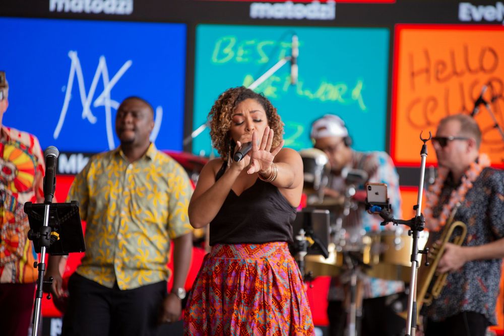 People dancing in colorful clothing at a lively social event with event signage visible in the background.