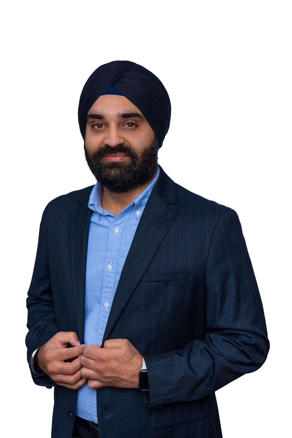 Professional portrait of a person in a navy suit and turban wearing a light blue dress shirt against a white background.