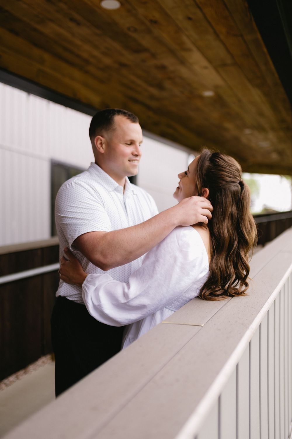 Couple sharing a romantic moment together on a covered porch with wooden beams overhead.