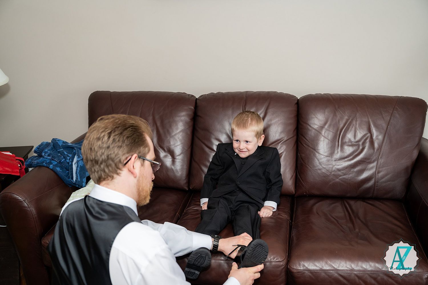 Parent sitting on floor in front of brown leather couch while playing with child in living room.