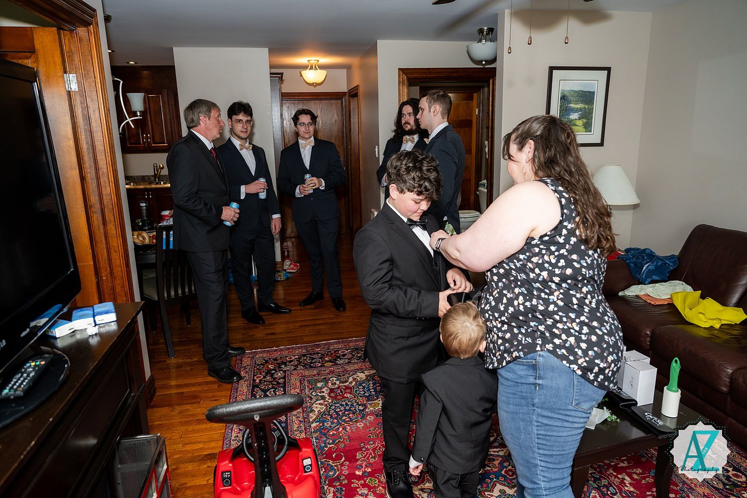 People mingling and socializing at an indoor event with hardwood floors and warm lighting.