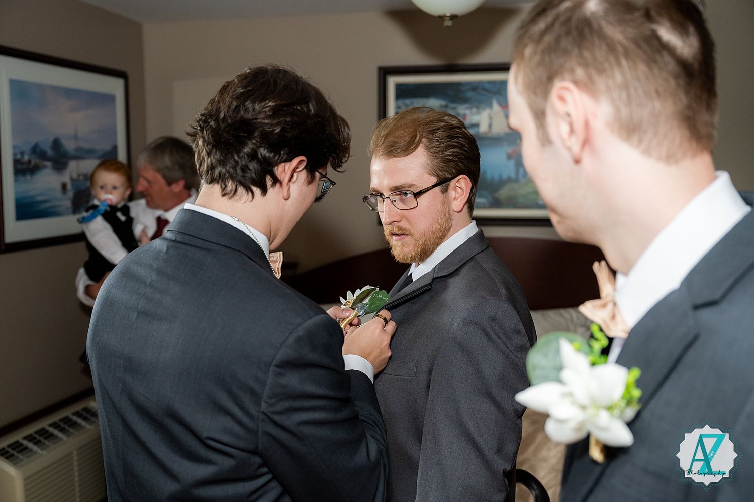 Groomsmen in black suits gather in preparation for a wedding celebration indoors.