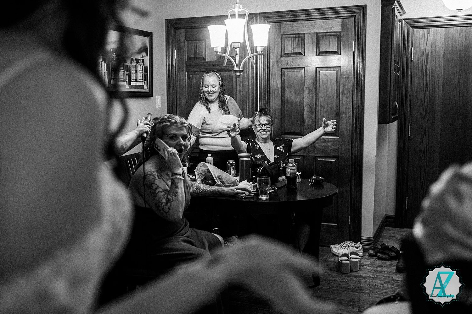 A cozy old-fashioned interior scene with people gathered in a dimly lit room with wooden furnishings and decor.