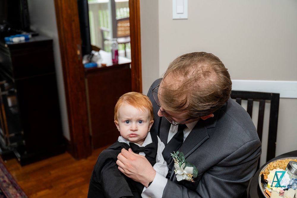 A tender moment captured at a formal event with a small child wearing formal attire and a boutonniere.