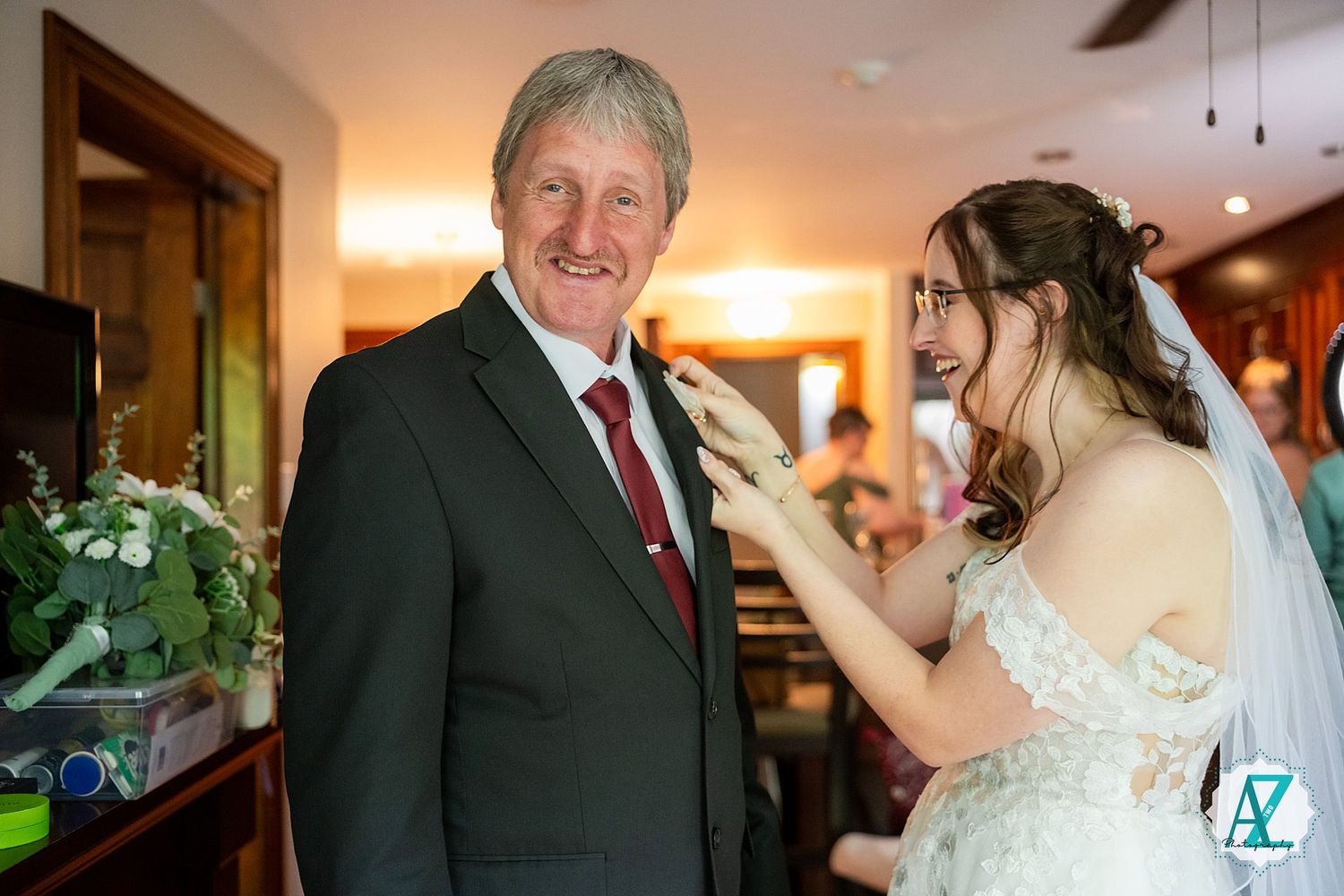An emotional moment at a wedding as a bride in a white gown shares a touching interaction in a warmly lit hallway.