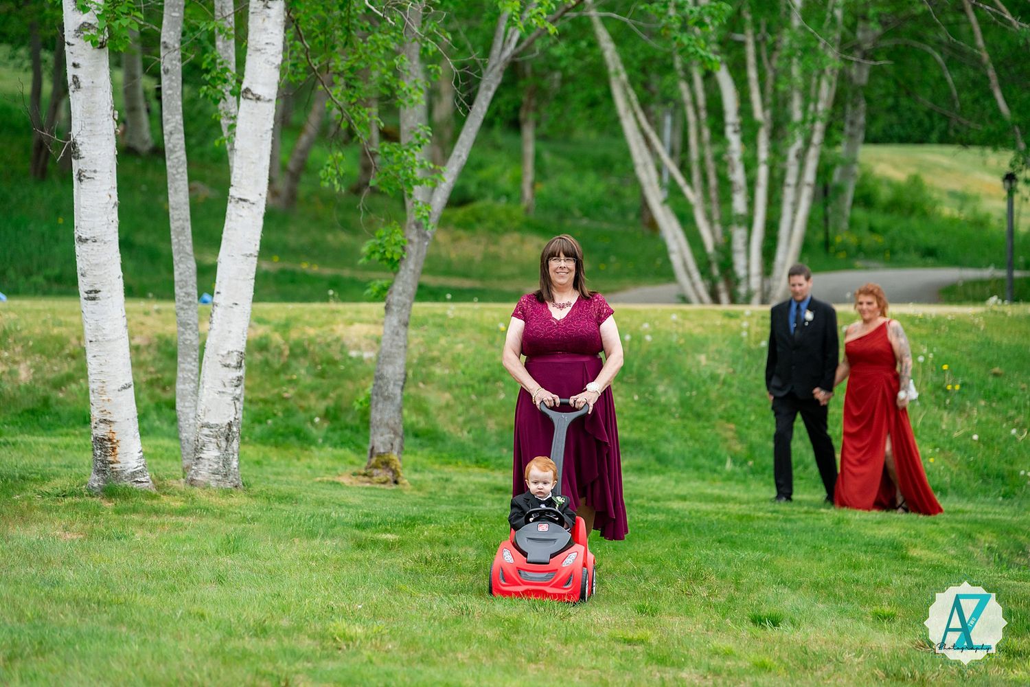 White birch trees line a grassy lawn where people gather for a formal outdoor event.