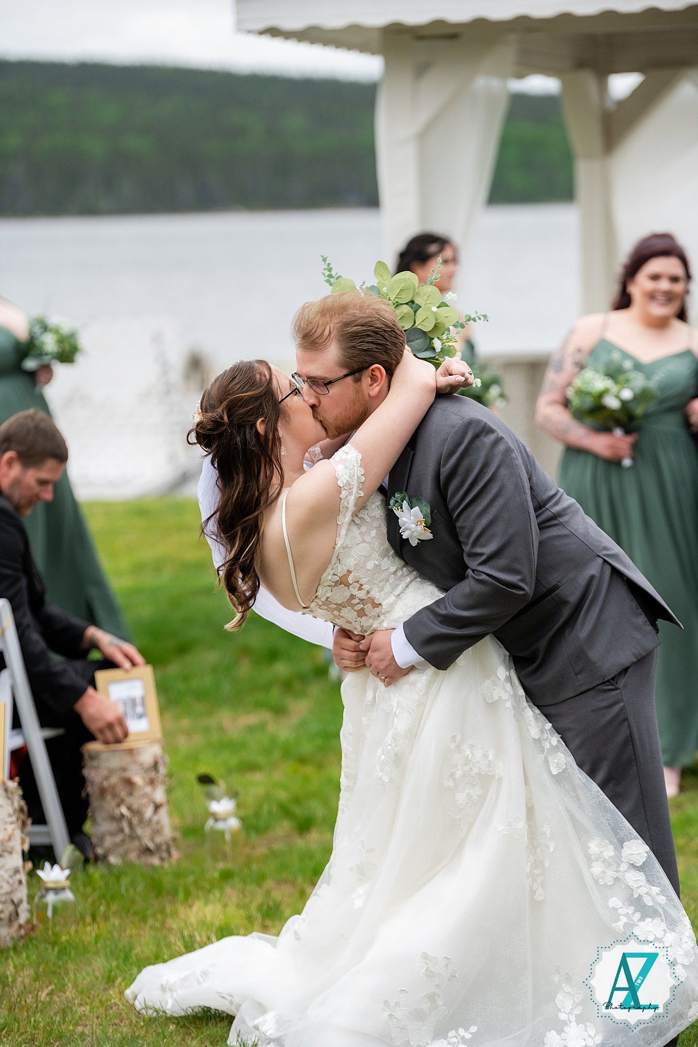 A romantic wedding couple shares a dramatic dip kiss in a scenic outdoor garden setting.