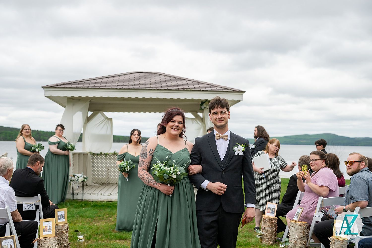 Wedding celebration takes place outside a coastal venue with green-clad bridesmaids and guests gathering.