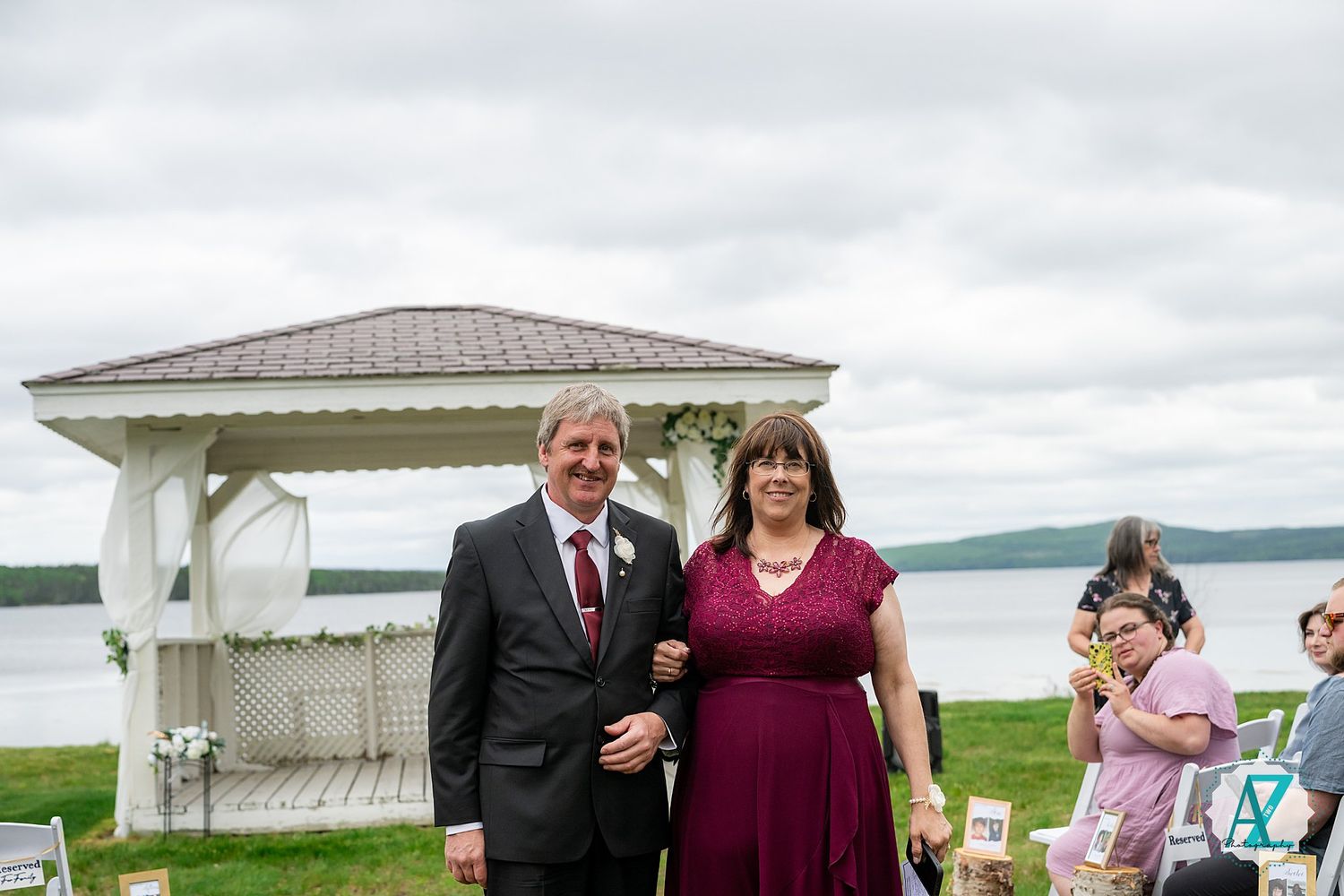 An outdoor wedding ceremony setup with white chairs and gazebo overlooking a scenic waterfront landscape.