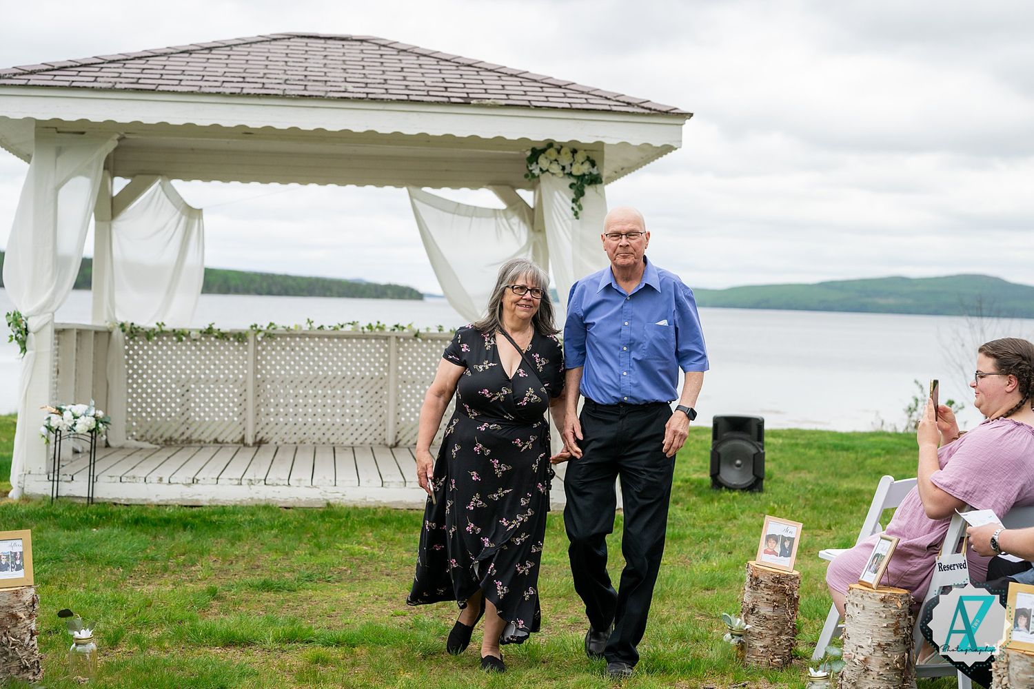 A scenic lakeside gazebo ceremony setup with rolling hills in the background on an overcast day.