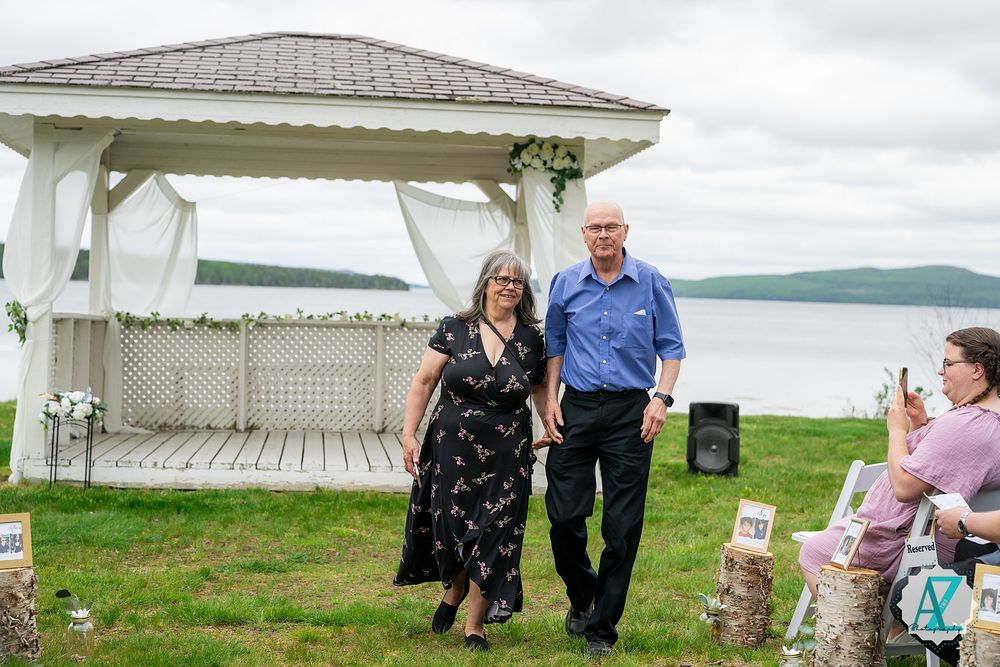 A scenic lakeside gazebo ceremony setup with rolling hills in the background on an overcast day.