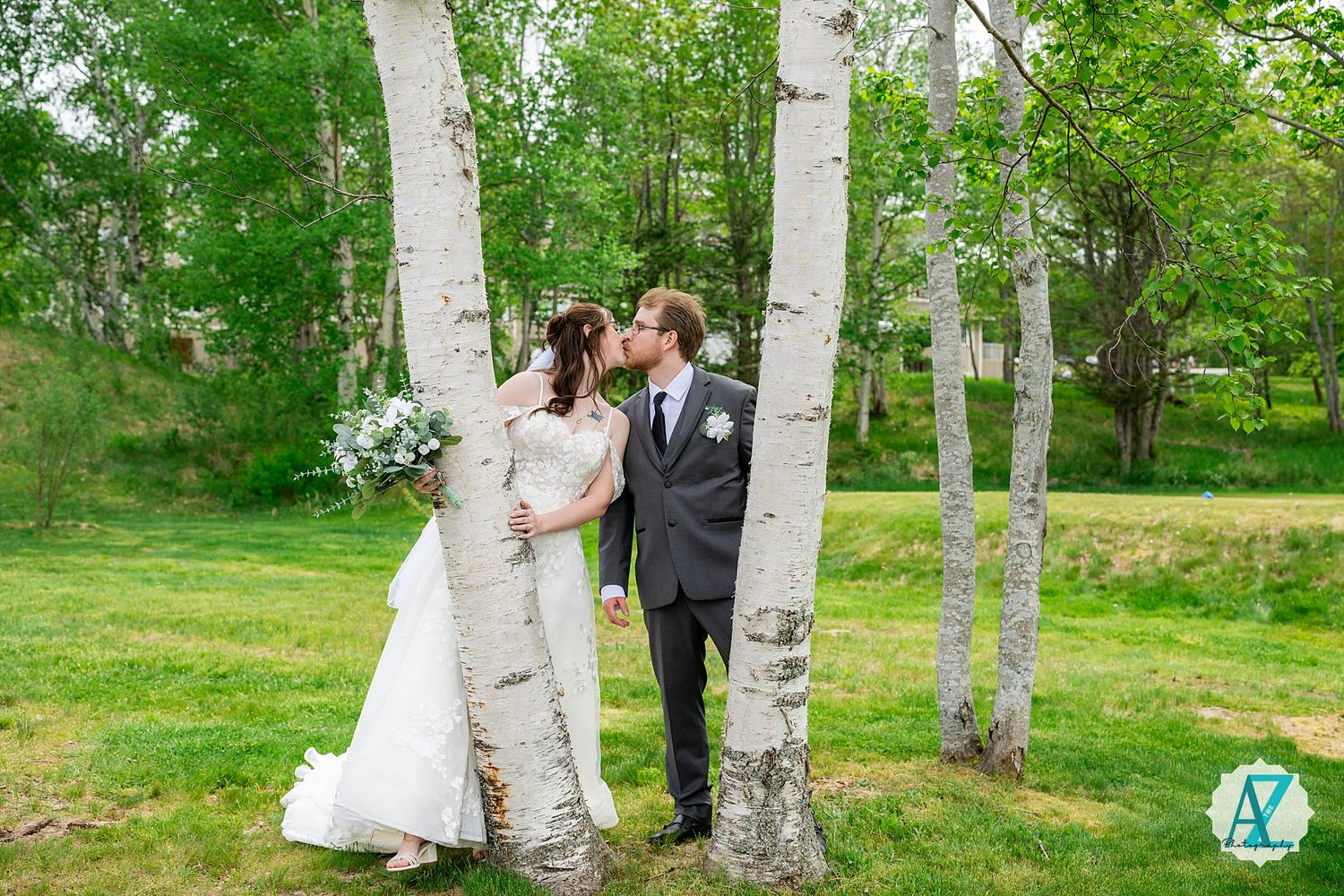 A romantic wedding portrait taken among white birch trees on a lush green lawn on a spring day.