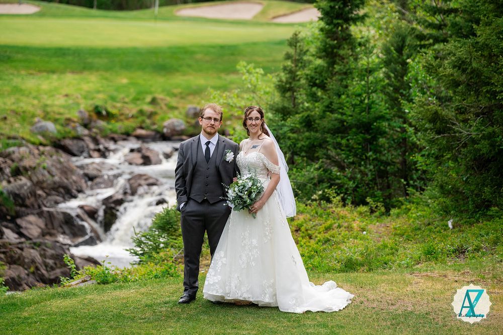 A couple poses by a rushing waterfall on their wedding day at a scenic mountain venue.