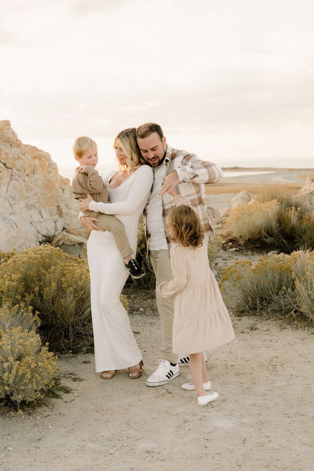 Family embraces and shares a joyful moment together on desert trail during golden hour.