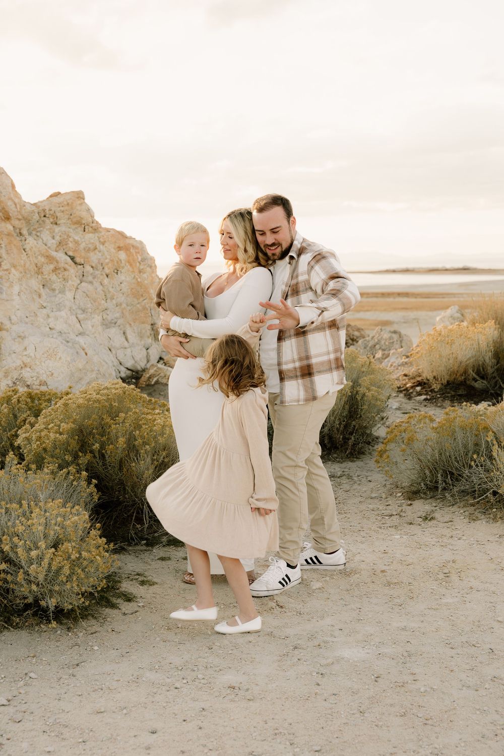Natural desert landscape photo shoot with family in coordinated cream and beige outfits at sunset.
