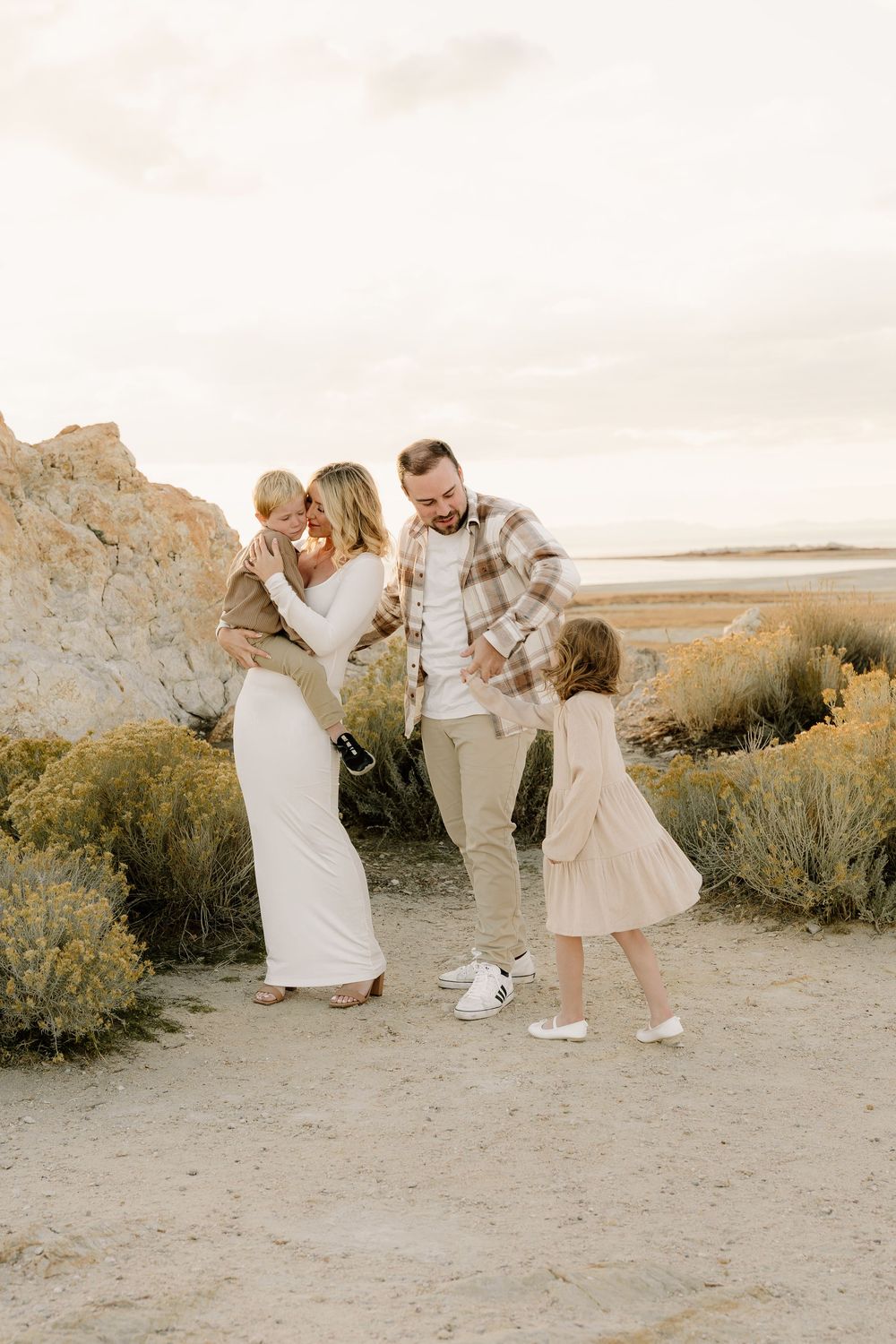 Family enjoying a sunset moment together on a desert trail with rock formations and desert brush in warm lighting.