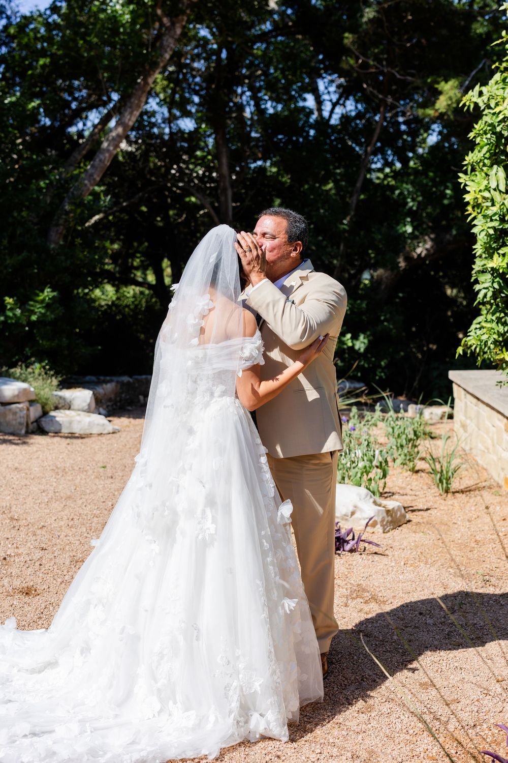 A tender moment between a bride and groom during their outdoor wedding on a gravel path.