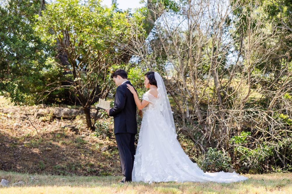 A bride and groom share an intimate moment outdoors surrounded by natural foliage on their wedding day.