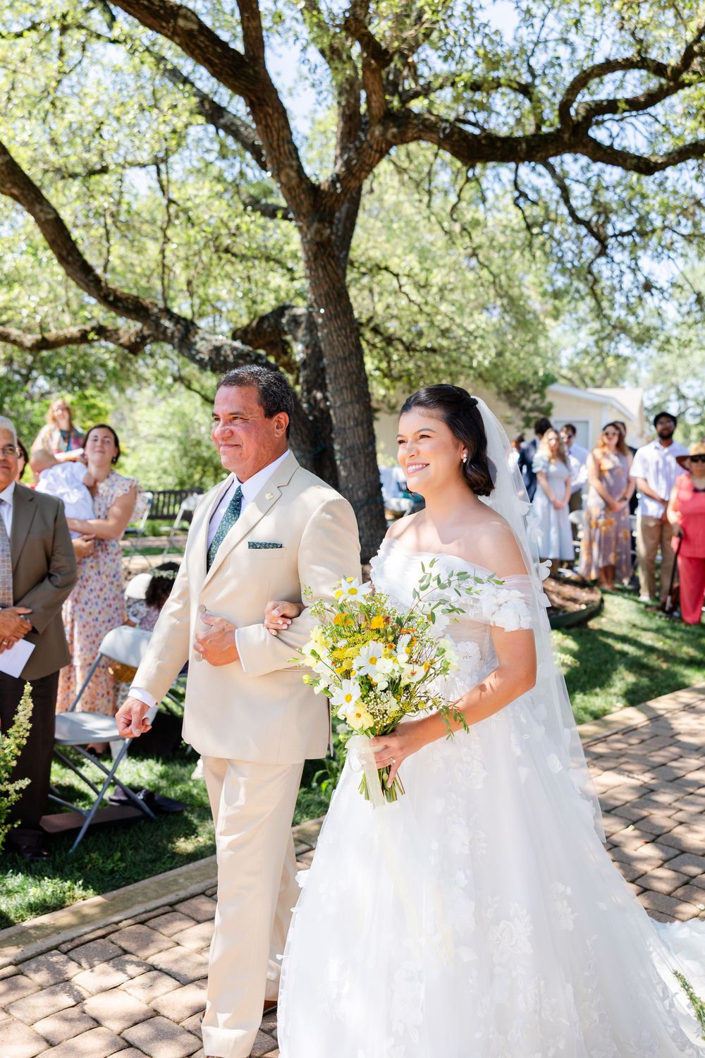A couple stands together during their outdoor ceremony beneath a majestic oak tree.