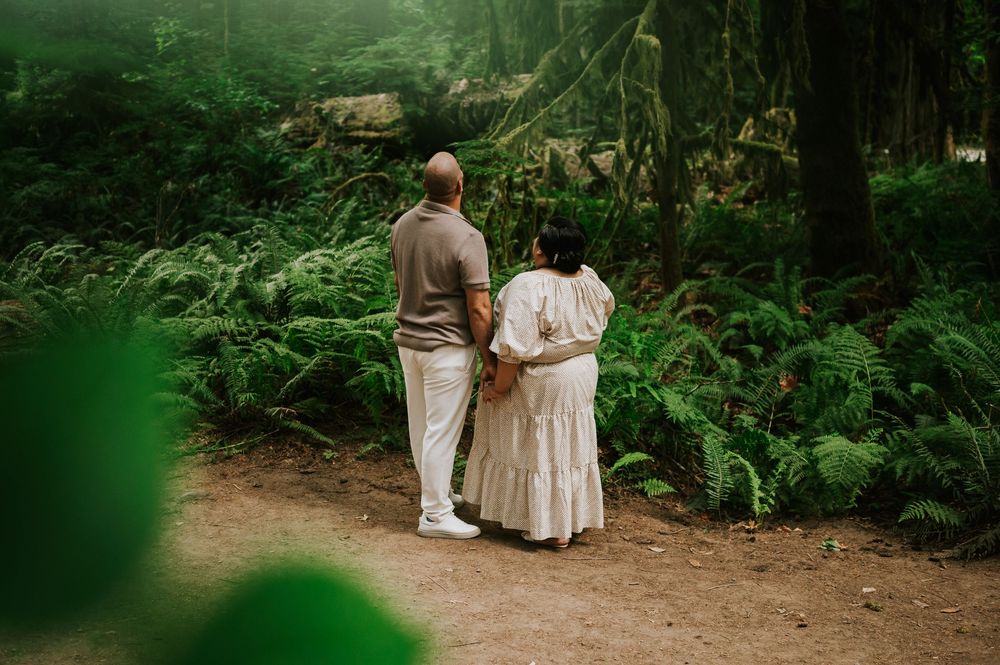 Photography of engaged couple looking at fir tree forest in Cathedral Groves, MacMillan Park. Vancouver Island adventure photographer