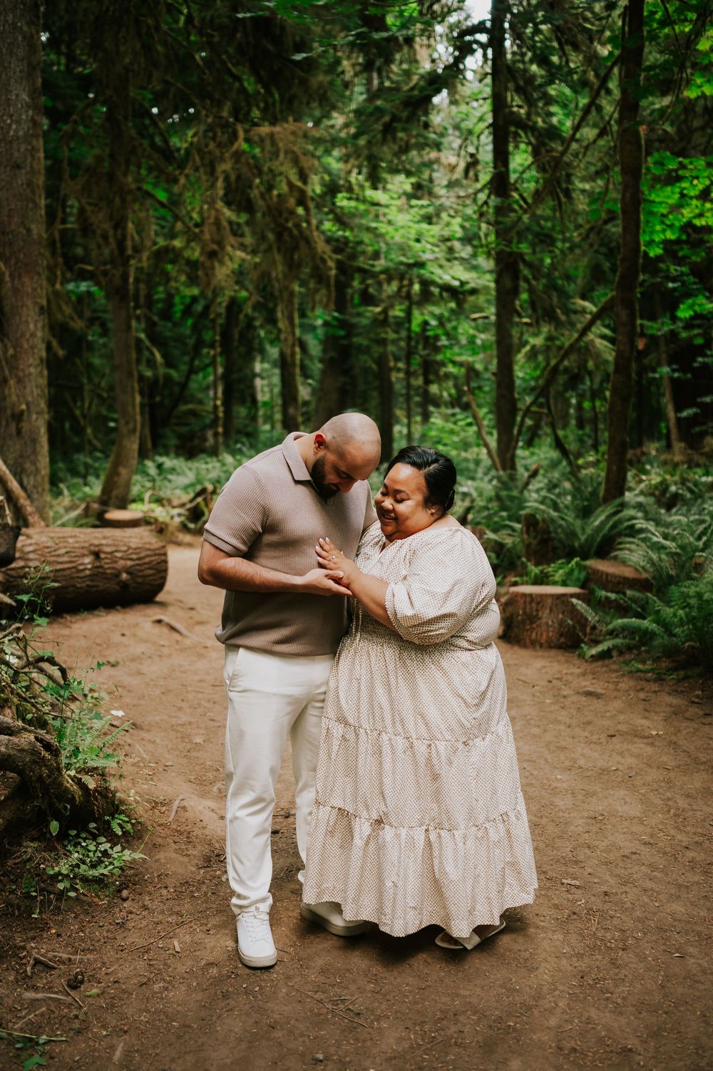 Photography of engaged couple looking at ring in Cathedral Groves, MacMillan Park forest. Vancouver Island adventure photographer