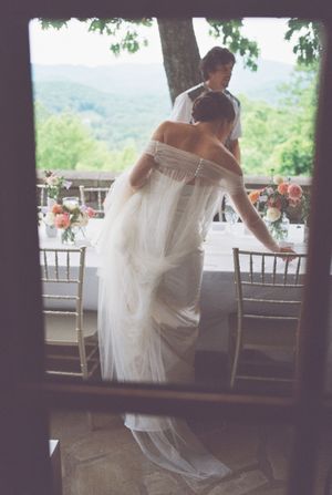 A wedding celebration at a scenic mountain venue with flowing white dress and elegant table settings in view.