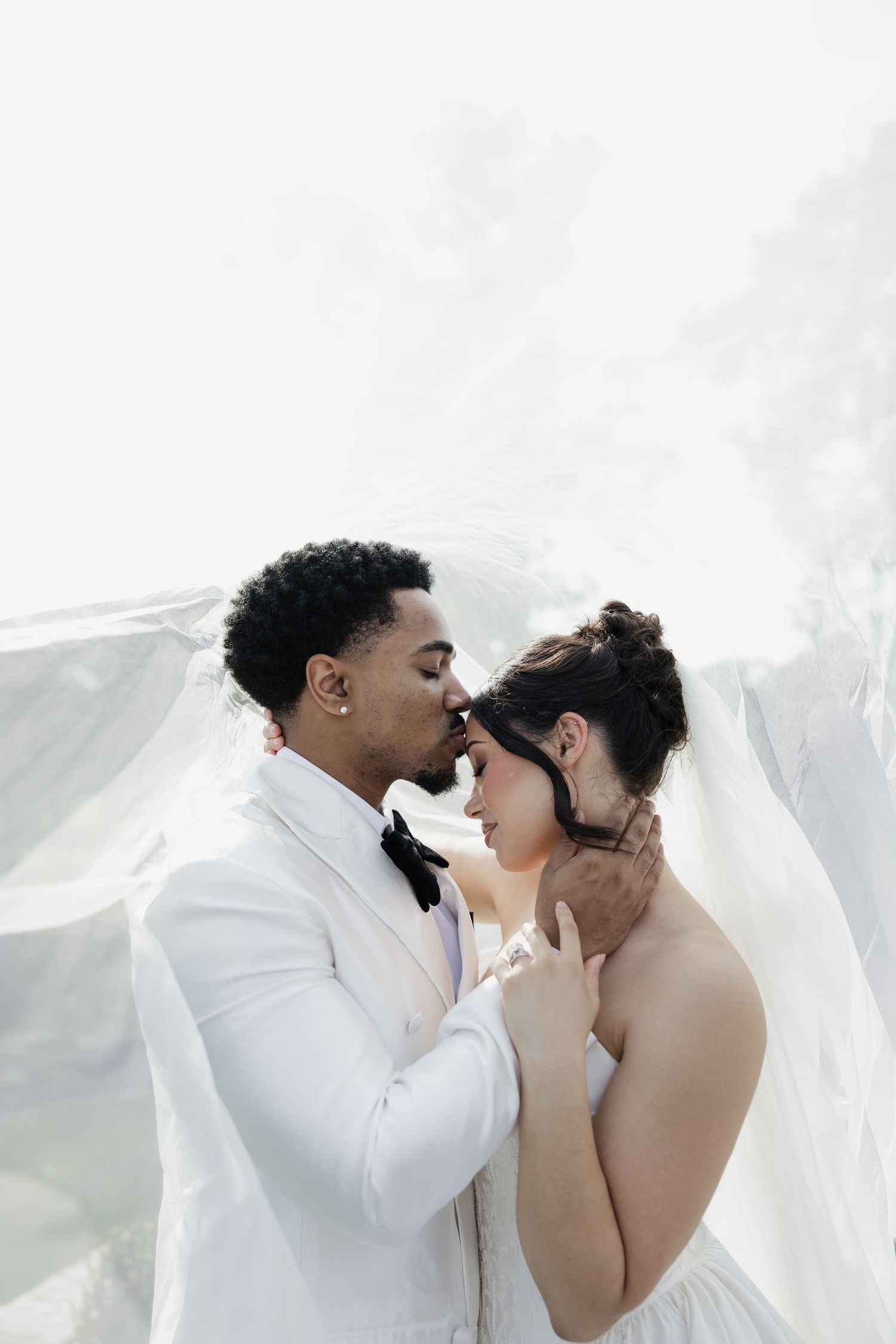 Playful wedding couple poses against white barn wall in sequence of romantic shots.