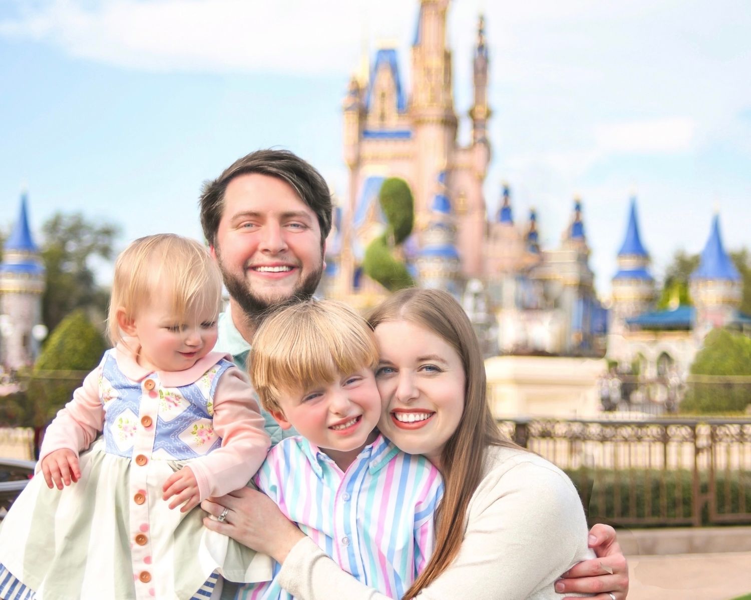A happy family poses together in front of Cinderella Castle at Walt Disney World Magic Kingdom theme park.