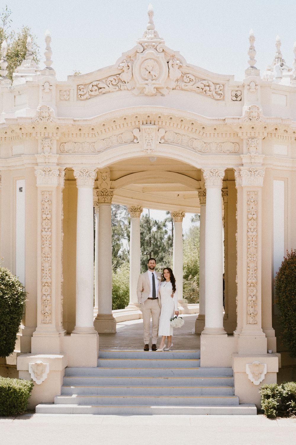 Elegant white marble colonnade with ornate architectural details and blue steps creates a romantic outdoor setting.