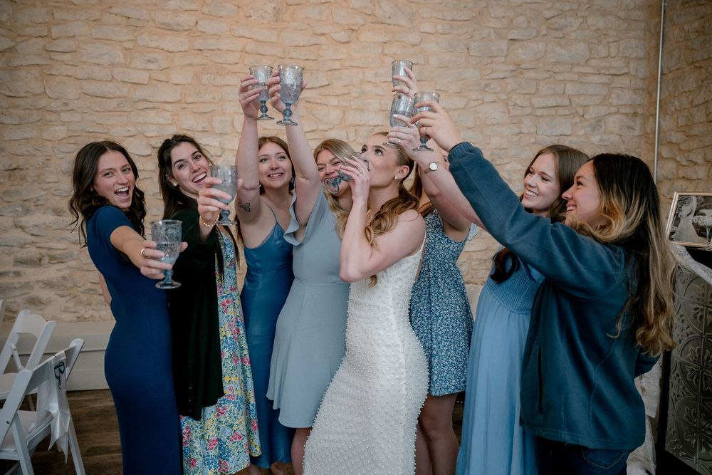 Candid moment of bride and bridesmaids raising drinks in celebration at a DFW wedding shower