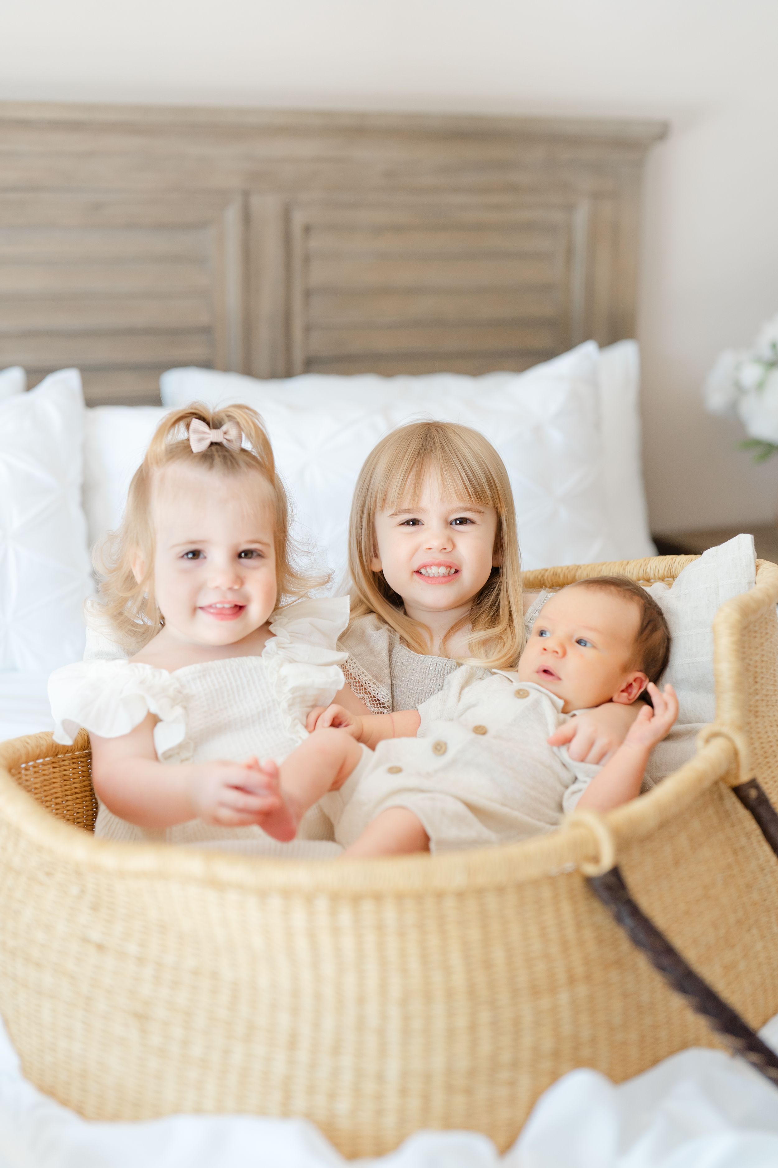 big sisters holding baby in a basket loving on their baby brother during his newborn session in st. Pete florida