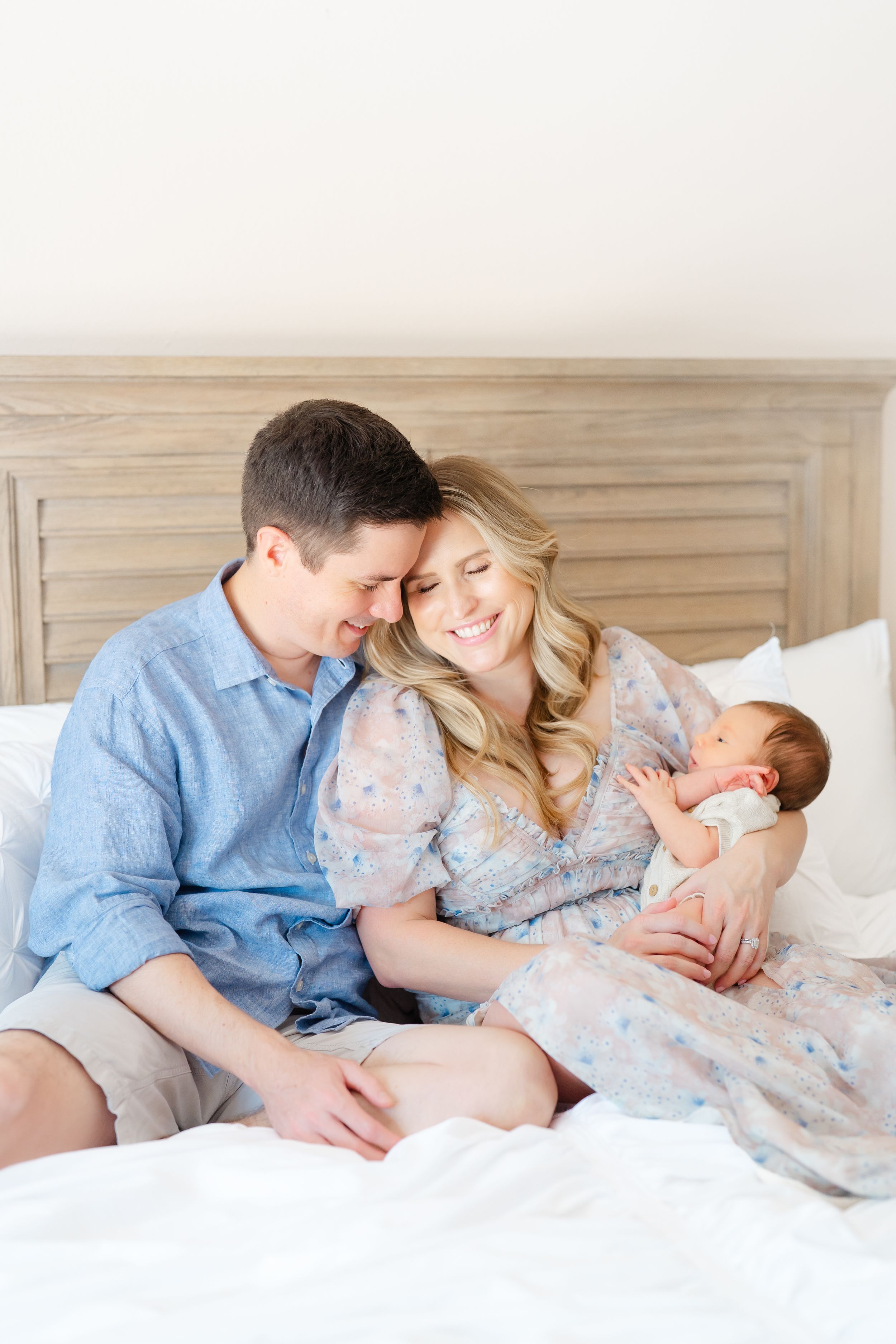 mom and dad snuggled up into each other holding their baby boy during his newborn session in Tampa florida