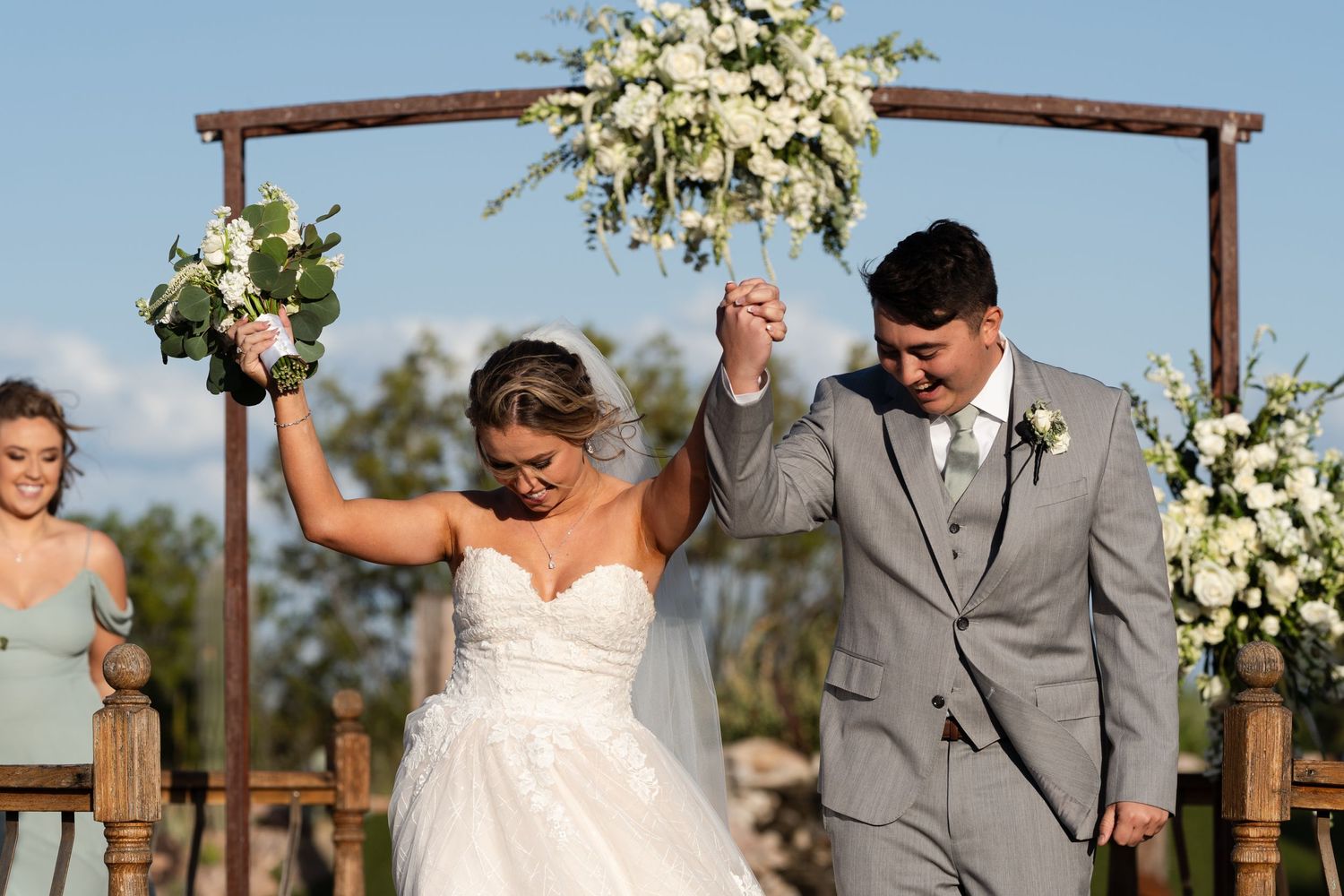 A candid photo of a newly married couple dancing down their wedding aisle to celebrate their love.