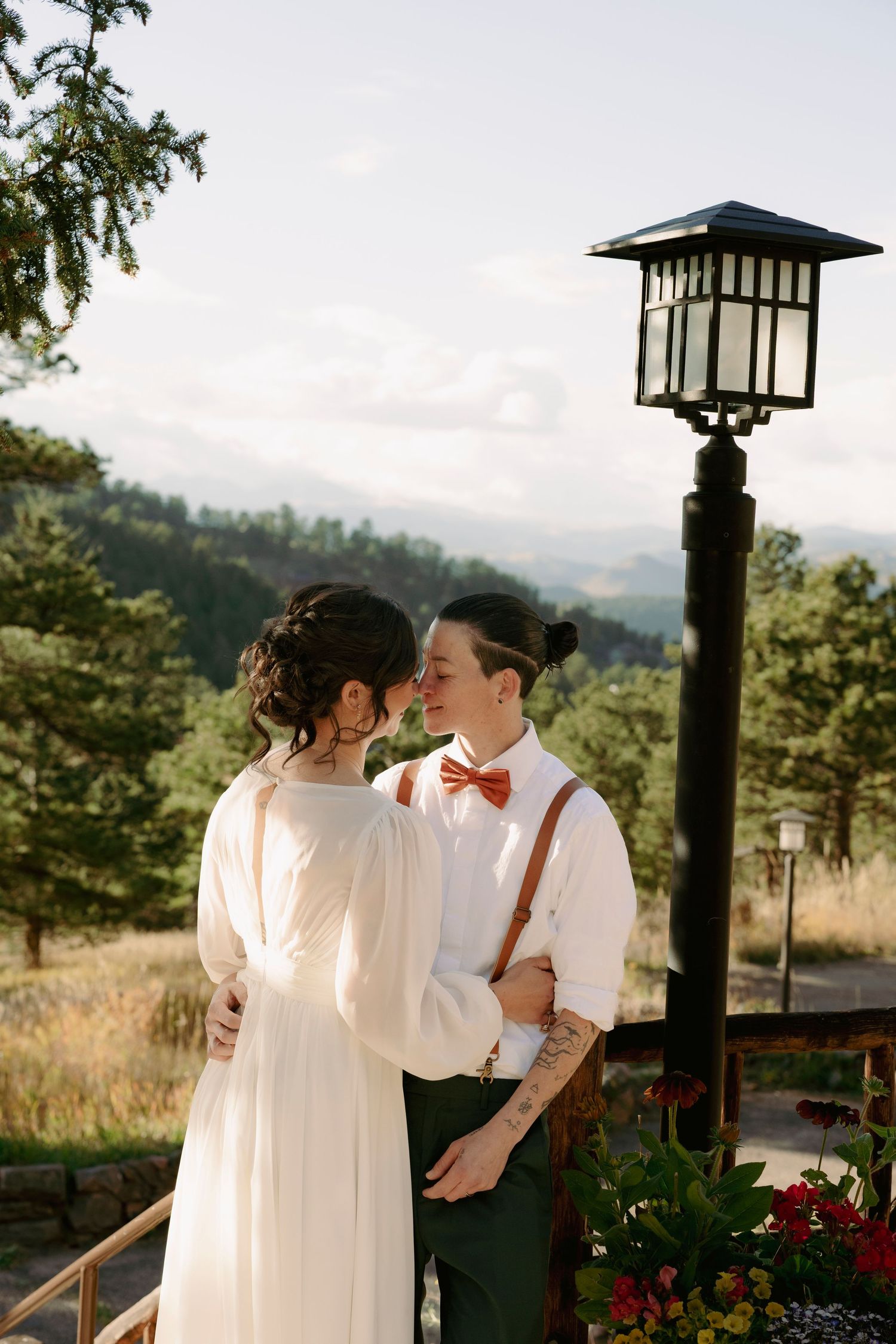 Intimate moment between two brides in white dresses with colorful wedding bouquet.