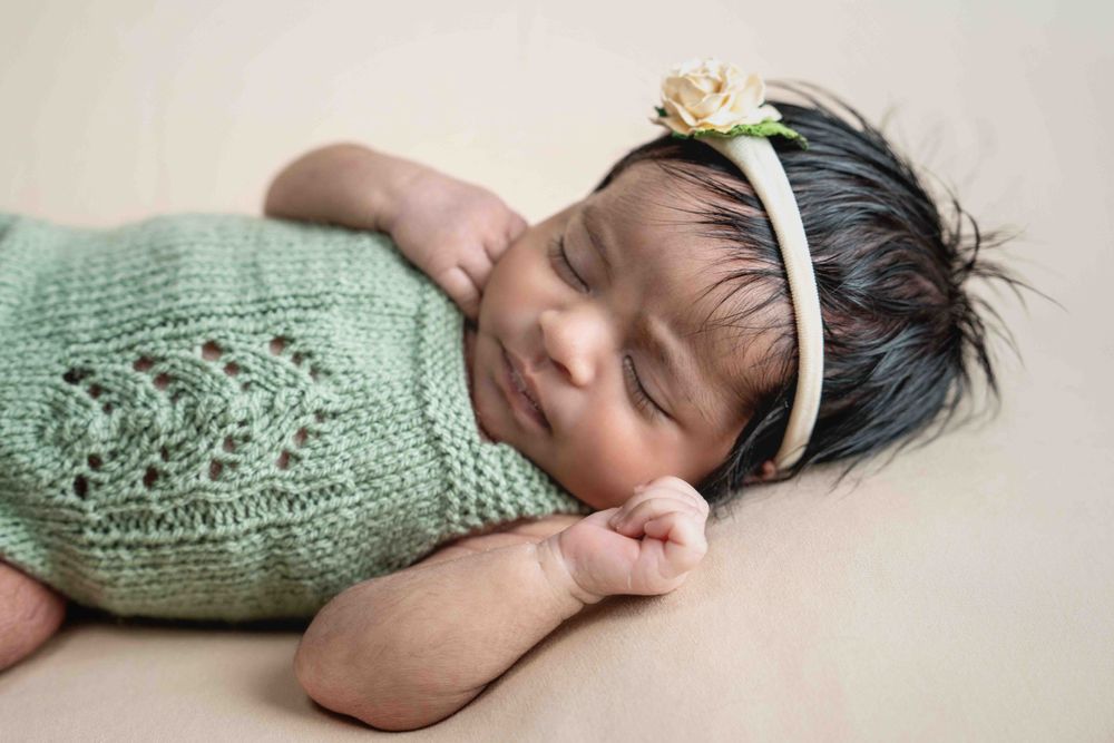 Professional studio photo of newborn baby girl in green and head bow