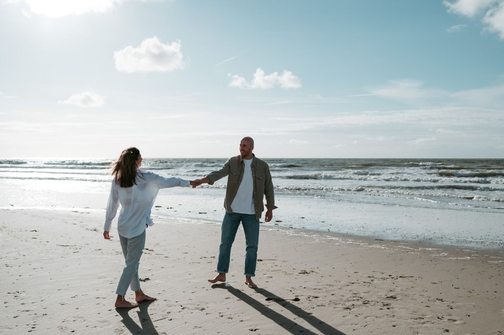 Melissa Stuer Photography Moederschapsfotograaf Moerbeke Oost-Vlaanderen zwangere vrouw en man dansend aan zee strand water blote buik
