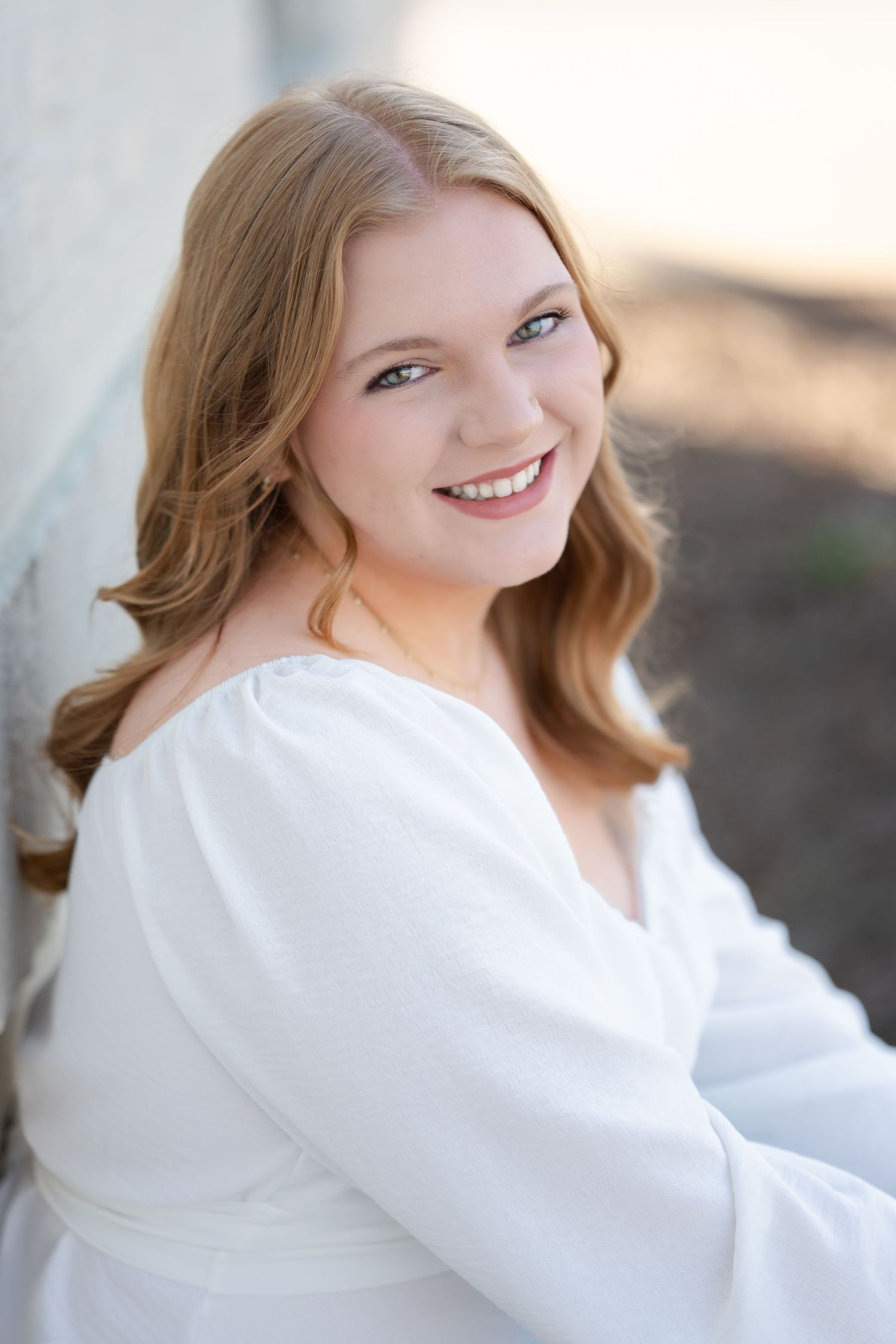 Portrait of a woman in a white sweater against a neutral background.