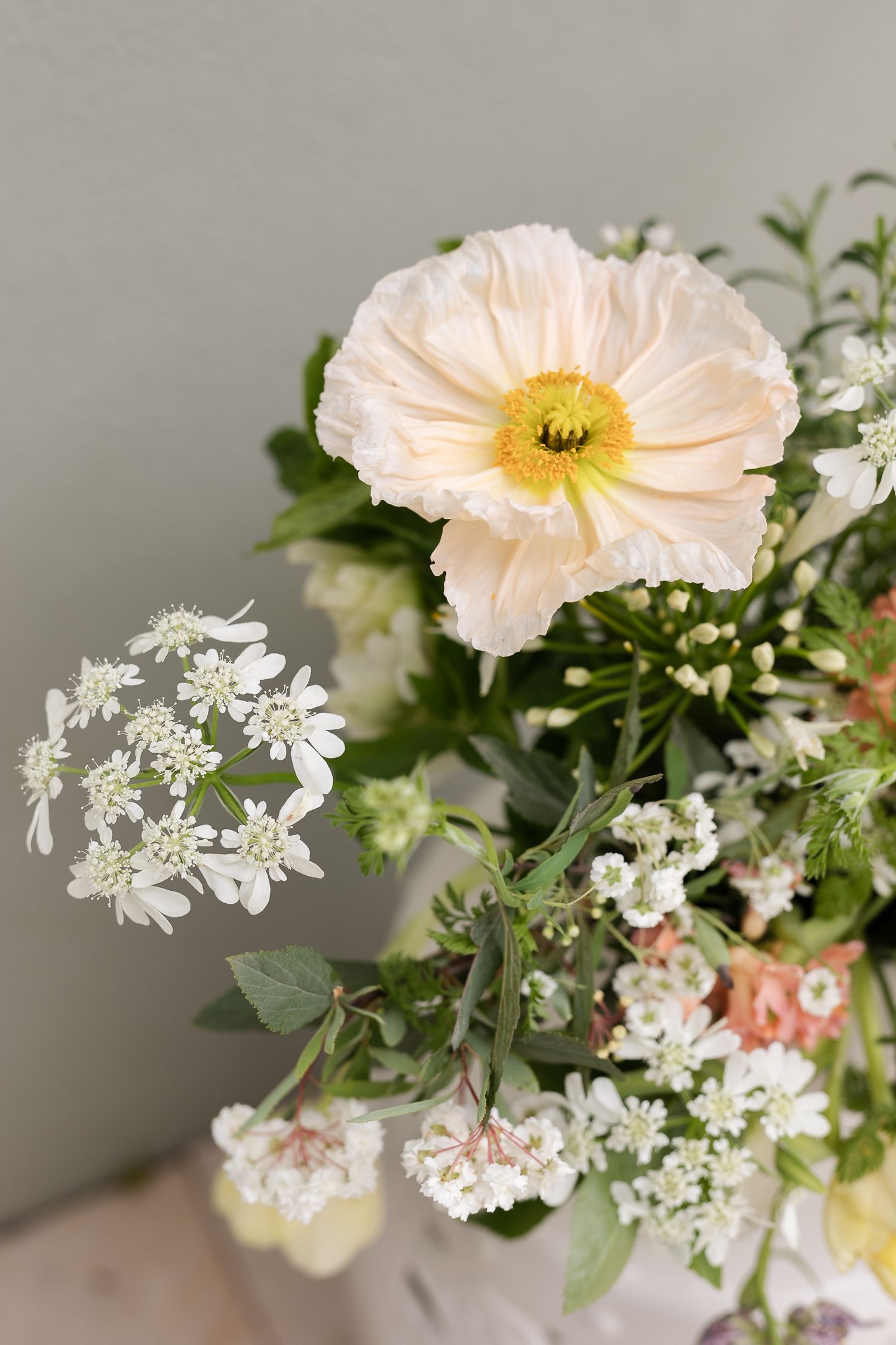 Decorative silver vases and seashells displayed on a wooden shelf against a stone background.