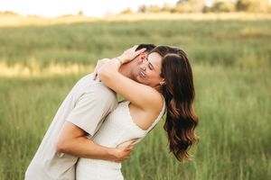 Joyful couple embracing in sunny meadow during golden hour in Branford, CT.