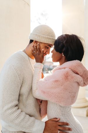 Couple in cozy winter whites sharing an intimate embrace indoors in Waterbury, CT.