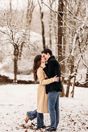 Couple sharing a romantic moment in a snowy winter forest in Bridgeport, CT.